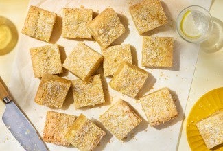 Alex Roberts Lemon Citrus Blondies on parchment paper atop a counter.