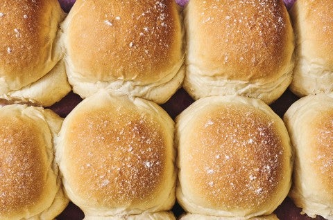 Close up of the golden tops of Big-Batch Quick Dinner Rolls on a sheet tray. - select to zoom