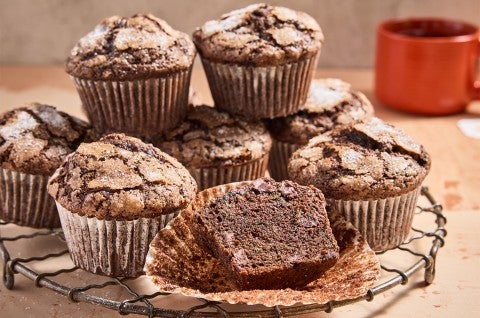 Chocolate Zucchini Muffins on a cooling rack with one halved - select to zoom