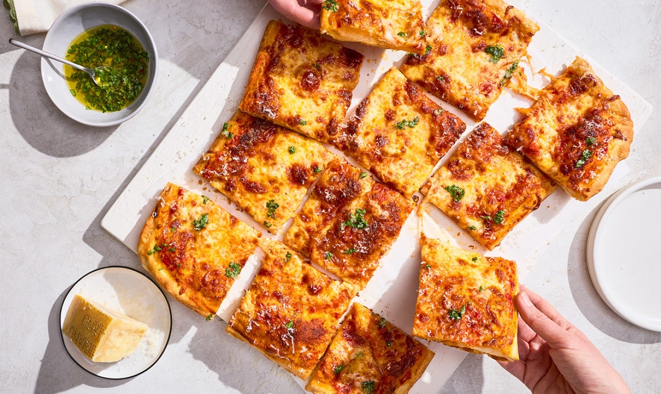 A sliced up Flaky Puff Crust Pizza with pieces being taken out