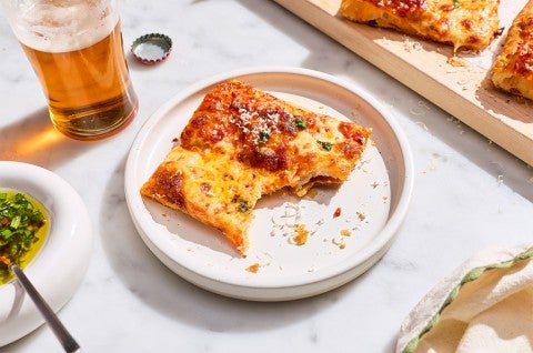 A slice of Flaky Puff Crust Pizza on a plate with a bite taken out of it - select to zoom