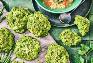 Green Goddess Herb Biscuits on cutting board with a bowl of soup in the frame.