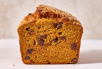 A loaf of The Most Pumpkin Pumpkin Chocolate Chip Bread cut into showing the interior
