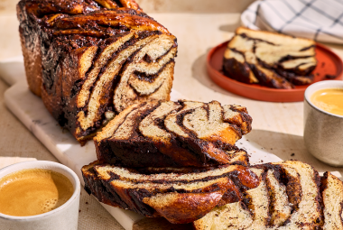Chocolate Sourdough Babka sliced and arranged on a table with coffee and other plates.